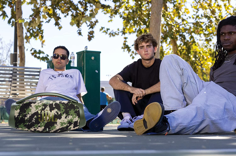 3 Männer sitzen um die JBL Boombox 3 in Camouflage
